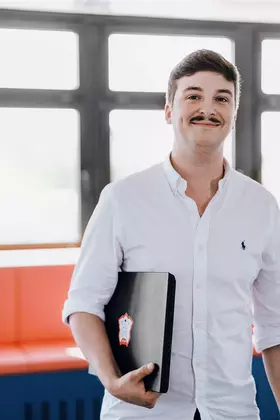 Student mit Laptop unterm Arm