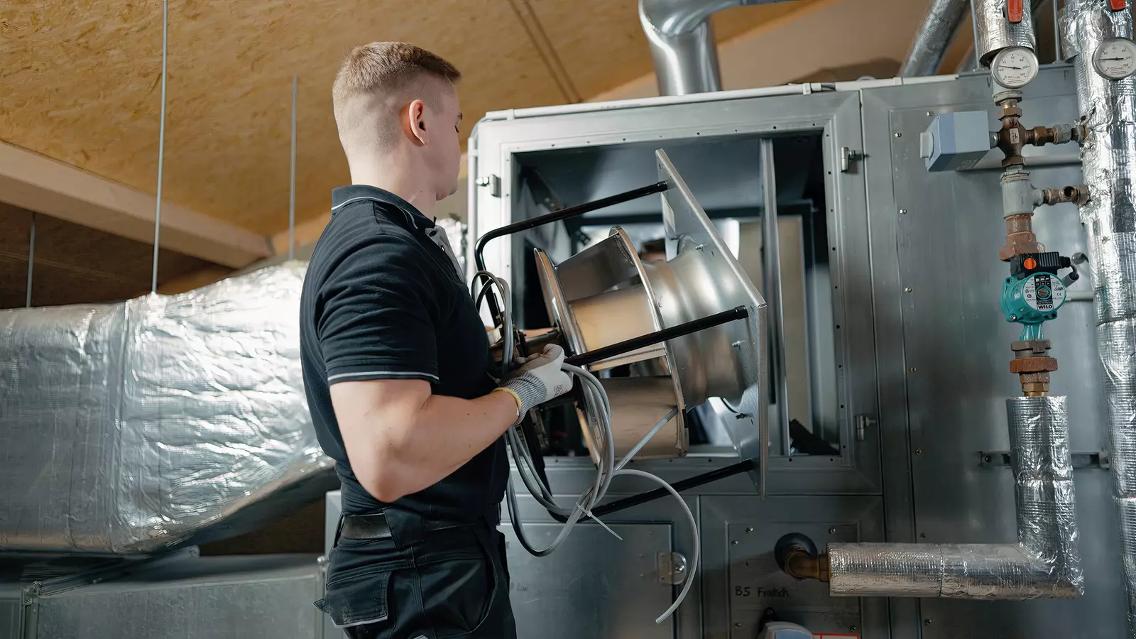 WOLF RLT-Service Monteur hebt neuen EC-Ventilator in ein älteres RLT-Gerät