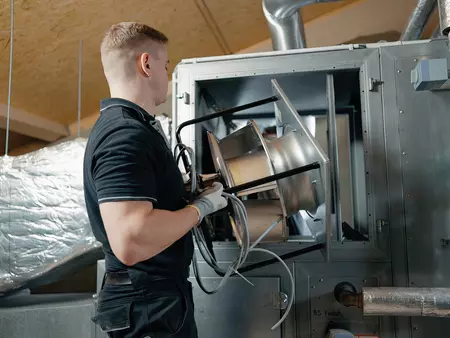 WOLF RLT-Service Monteur hebt neuen EC-Ventilator in ein älteres RLT-Gerät