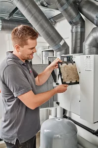 Ein Monteur tauscht den Filter im Wohnraumlüftungsgerät