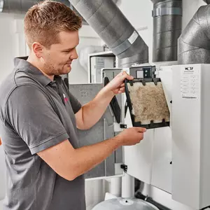 Ein Monteur tauscht den Filter im Wohnraumlüftungsgerät