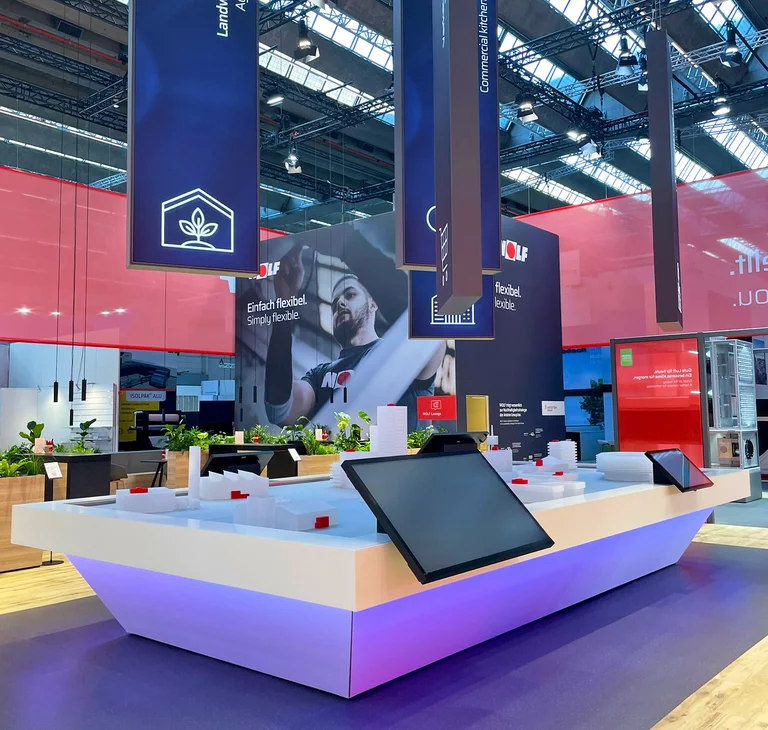 Messestand von WOLF mit dem beleuchteten Ecosystem, hängenden Bannern sowie modern gestalteten Informationsflächen