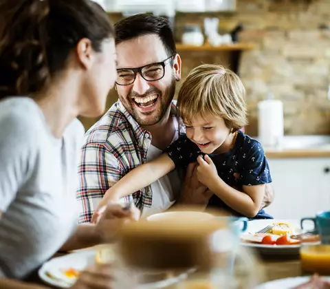 Familie scherzt beim Frühstück Zuhause