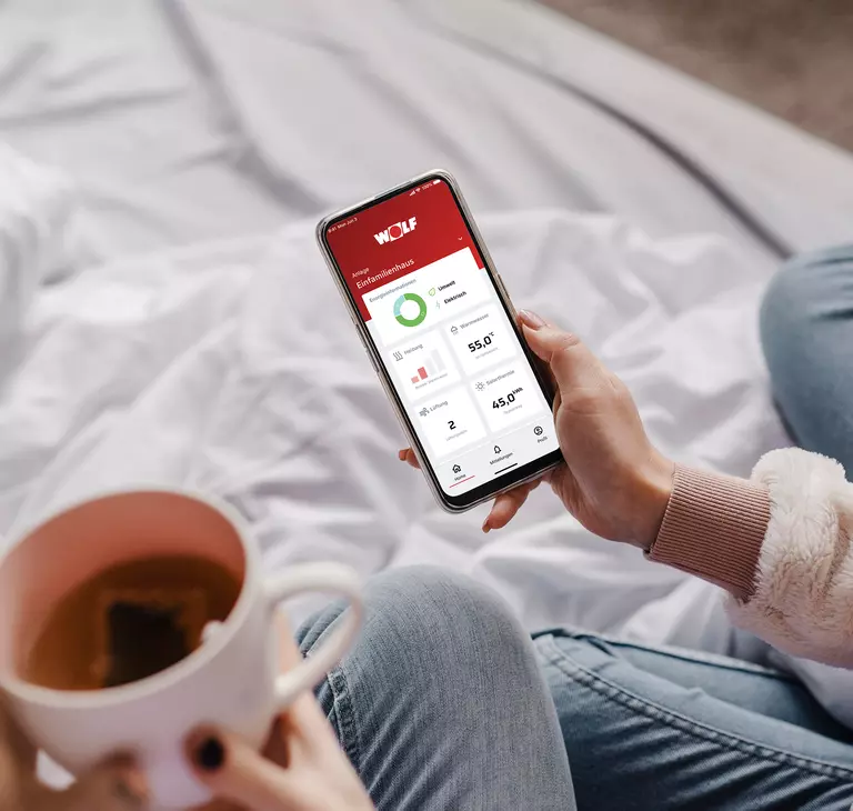 Eine Frau steuert mit ihrem Handy die Heizung 