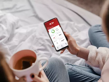 Eine Frau steuert mit ihrem Handy die Heizung 