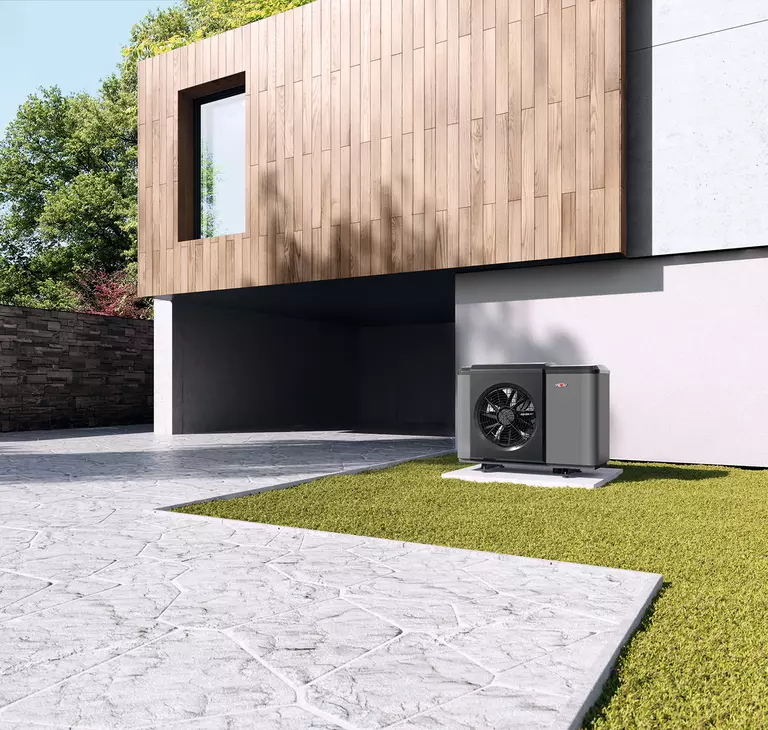 Eine WOLF Wärmepumpe neben der Einfahrt der Garage  