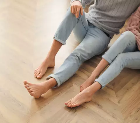 Zwei Füße auf einem Parkettboden