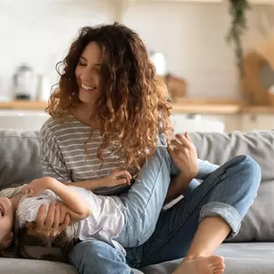 Mama scherzt auf Couch mit Kind