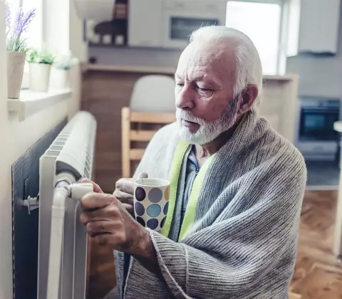 Älterer Herr friert vor Heizkörper