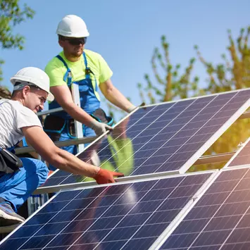 Bauarbeiter befestigen eine Photovoltaikanlage auf dem Dach 