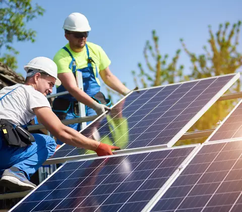 Bauarbeiter befestigen eine Photovoltaikanlage auf dem Dach 