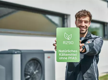 WOLF Mitarbeiter hält Schild mit Aufschrift 'R290 natürliches Kältemittel'