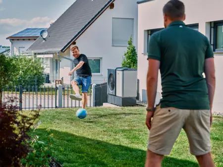 Kunden spielen Fußball neben Wärmepumpe