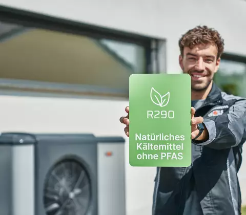 WOLF Mitarbeiter hält Schild mit Aufschrift 'R290 natürliches Kältemittel'