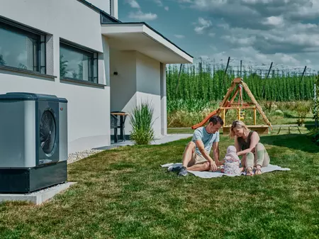 Familie mit Baby im Garten neben Wärmepumpe