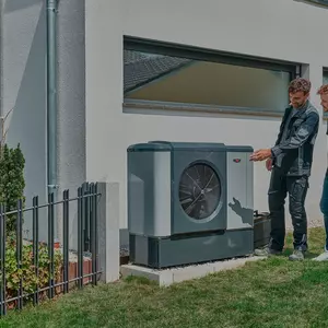 WOLF Mitarbeiter und Kunde betrachten Wärmepumpe im Garten