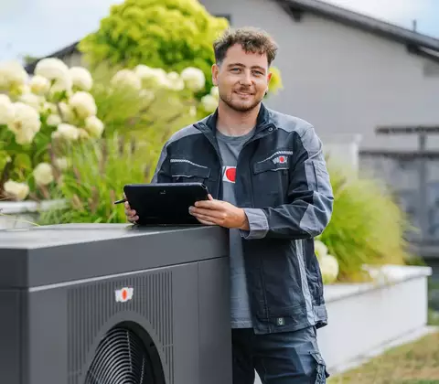 Servicetechniker mit Tablet an WOLF CHA SE Wärmepumpe im Garten