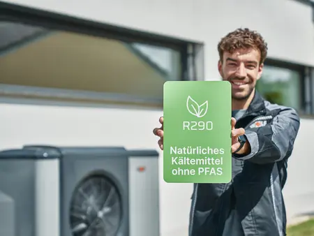 WOLF Mitarbeiter hält Schild mit Aufschrift 'R290 natürliches Kältemittel'
